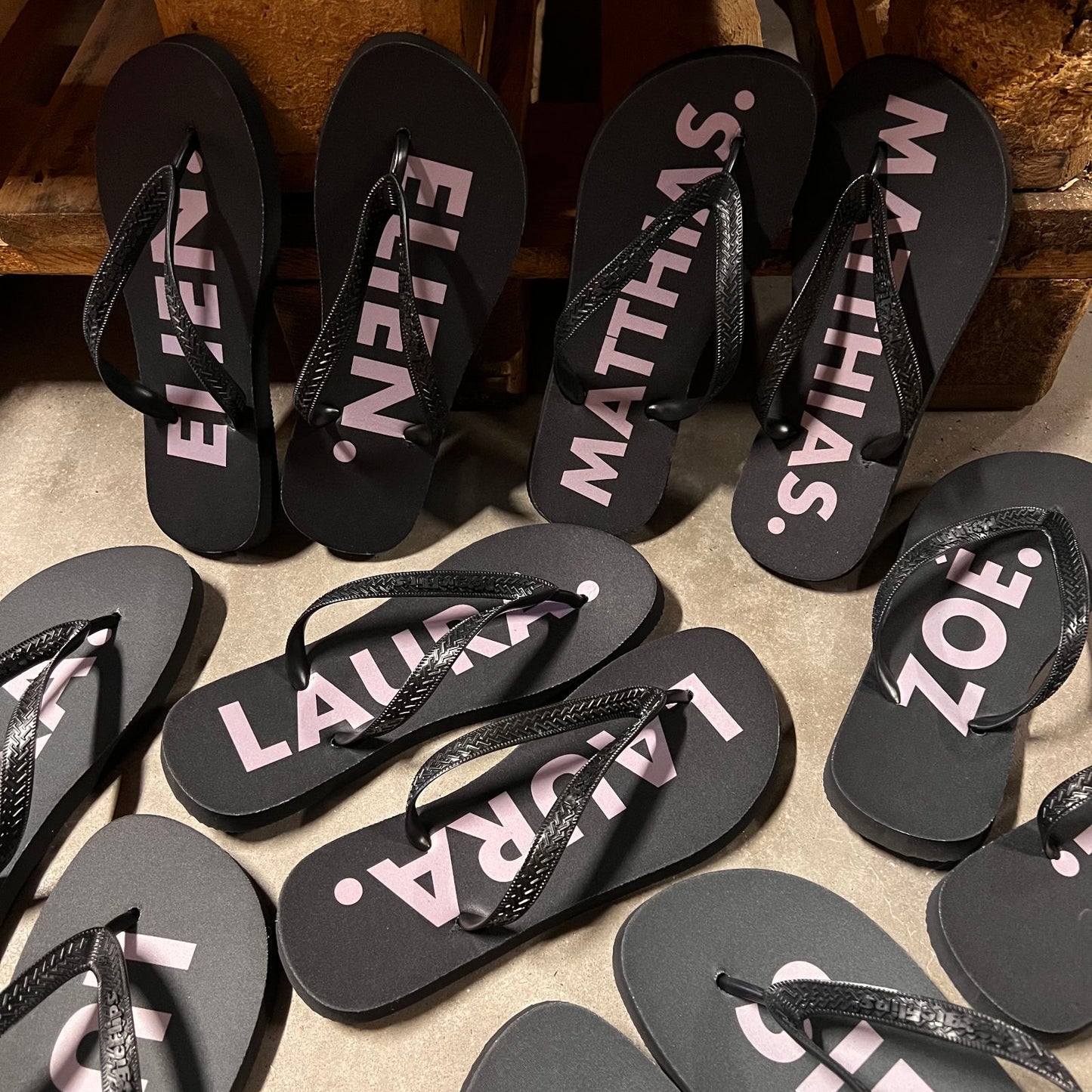 Zwarte gepersonaliseerde slippers met naam in roze letters, besteld voor een bruiloft of feest