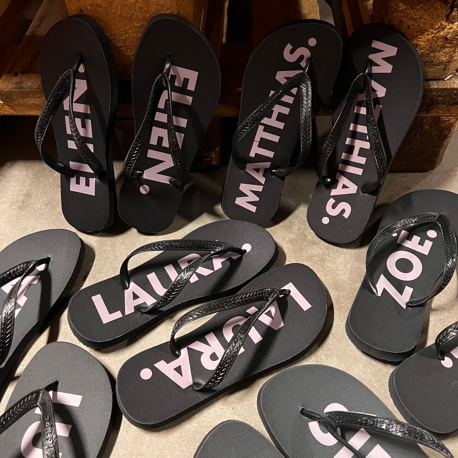 Zwarte gepersonaliseerde slippers met naam in roze letters, besteld voor een bruiloft of feest