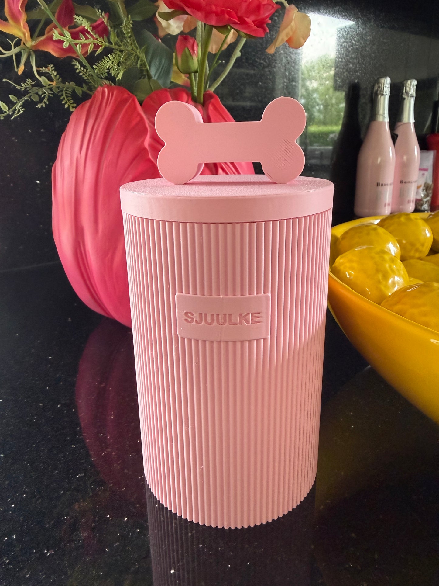 Roze snackpot met naam Sjuulke op een zwart aanrecht met bloemen